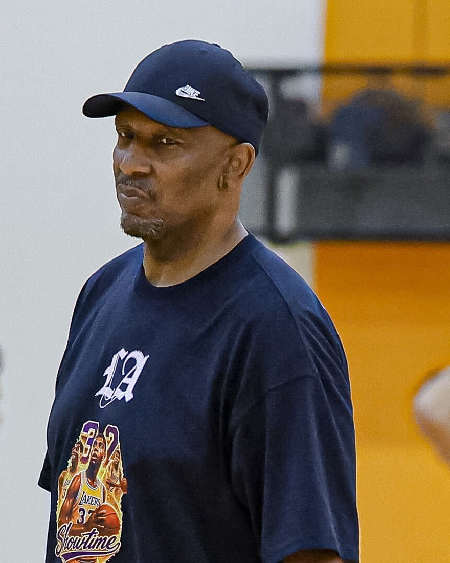 Ron Wilson watching a game from the sideline in a Lakers Showtime shirt and cap